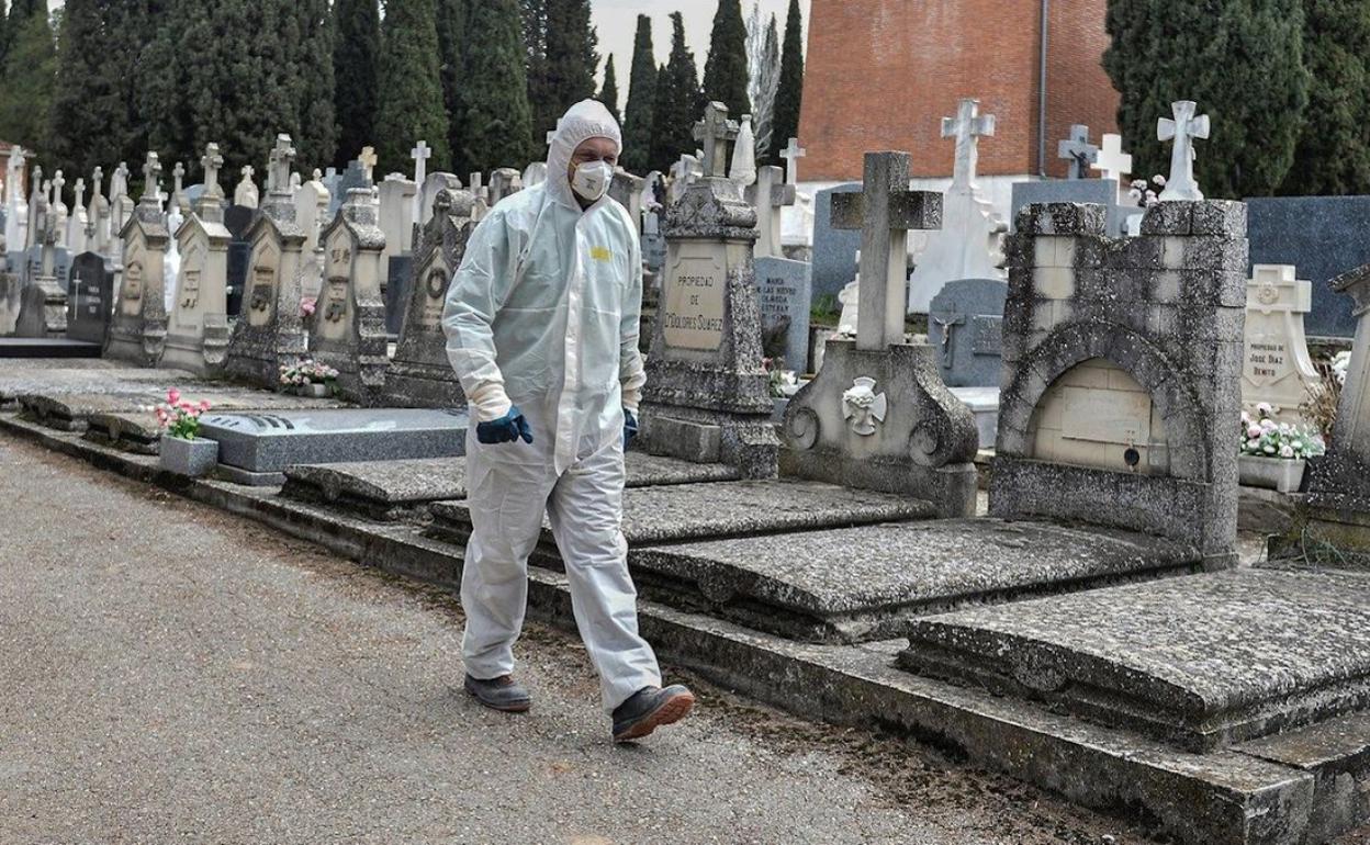 Imagen de un cementerio con un trabajador con un equipo EPI. 