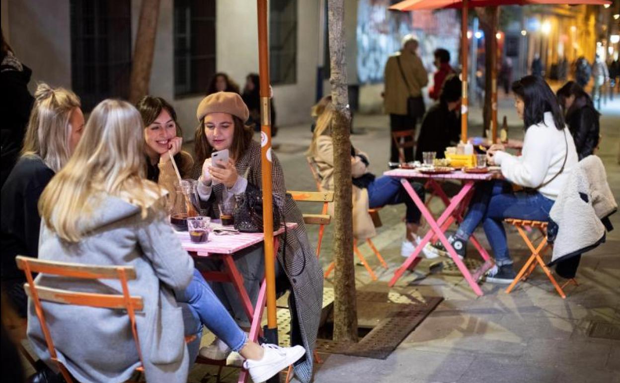 Varias personas conversan en la terraza de un bar de Barcelona.