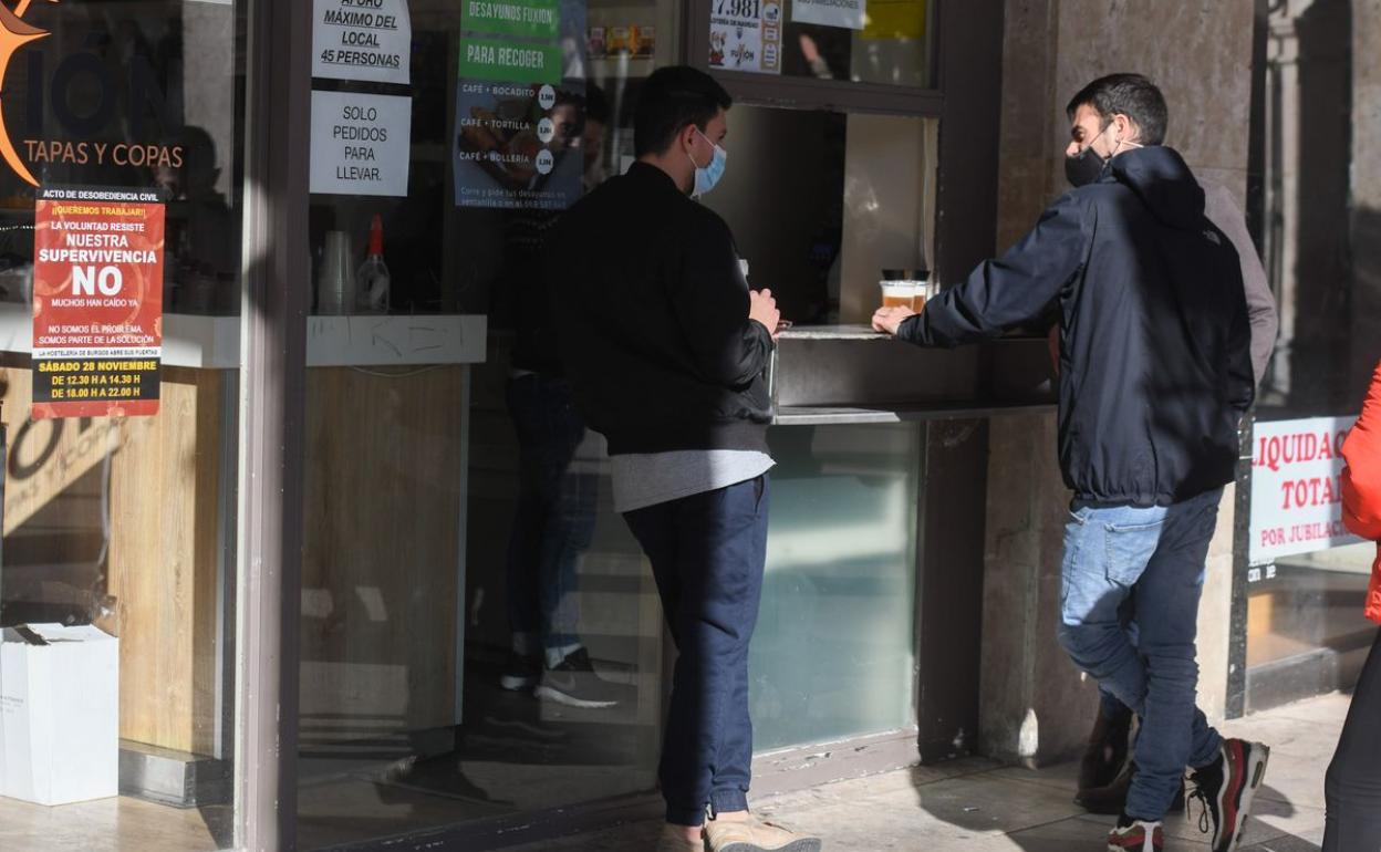 Dos jóvenes apoyados en la barra de un establecimiento hostelero de Burgos.