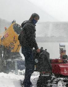 Imagen secundaria 2 - De izquierda a derecha: 1ºUn hombre pasea junto a una máquina quitanieves, 2º Una de las pistas de San Isidro nevada, 3º Un hombre relizada tareas de acondicionmiento en una de las pistas.