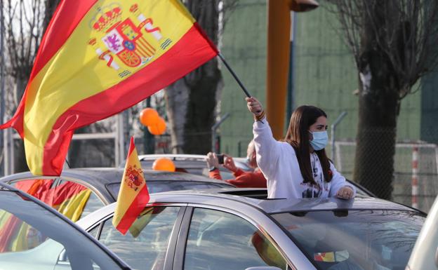 Galería. Una joven levanta una bandera desde el interior de un vehículo.