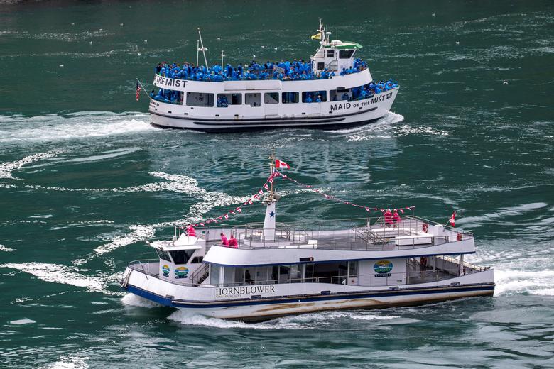 Canadá | El barco turístico estadounidense Maid Of The Mist, limitado al 50 % de ocupación según las reglas del estado de Nueva York en medio de la propagación del coronavirus, pasa junto a un barco canadiense limitado según las reglas de Ontario a solo seis pasajeros, en Niagara Falls