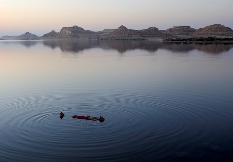 Egipto | Un egipcio nada en un lago frente al Taghaghien Island Resort en el desierto occidental de Egipto después de que el gobierno cancelara la celebración del festival de la paz de Siyaha