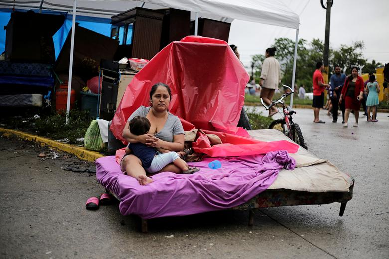 Honduras | Una mujer amamanta a su hijo mientras se sienta en su cama afuera de un área inundada durante el paso de la tormenta Eta, en La Lima, Honduras