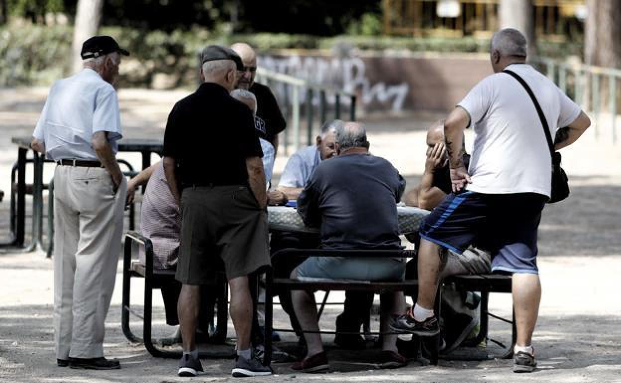 Un grupo de pensionistas en un parque jugando la partida.