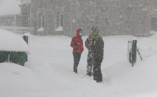 Tres personas bajo la nieve en Pajares.