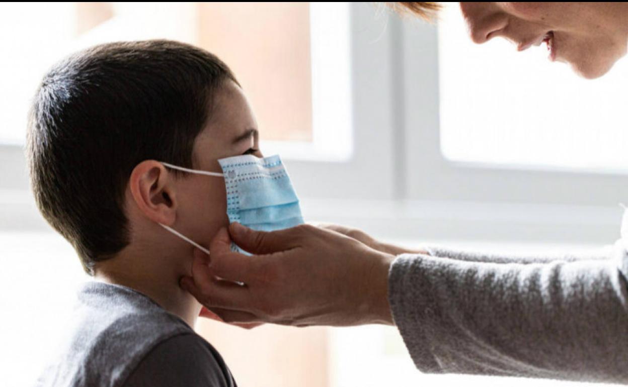 Una mujer coloco una mascarilla a su hijo. 