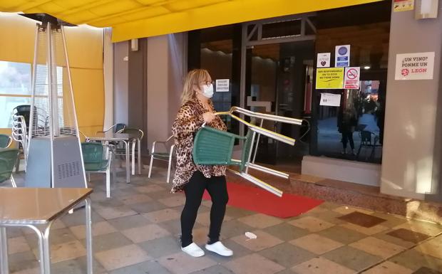 La dueña de un bar retira las mesas de su terraza antes de las seis. 