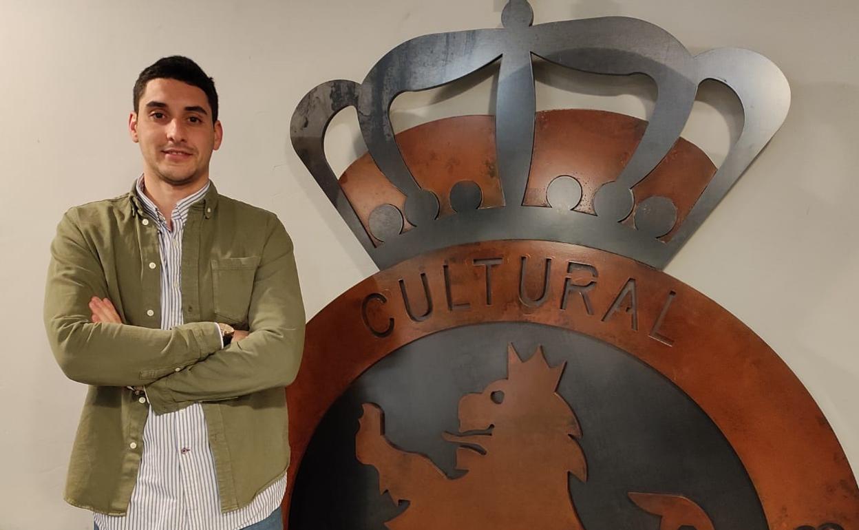 Brais Acebal posa junto al escudo de la Cultural y Deportiva Leonesa.