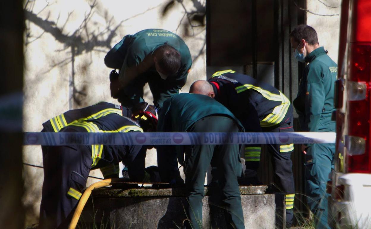 Bomberos y agentes de la Guardia Civil se asoman al pozo donde este domingo fue hallado un cadáver, en el municipio pontevedrés de O Porriño.