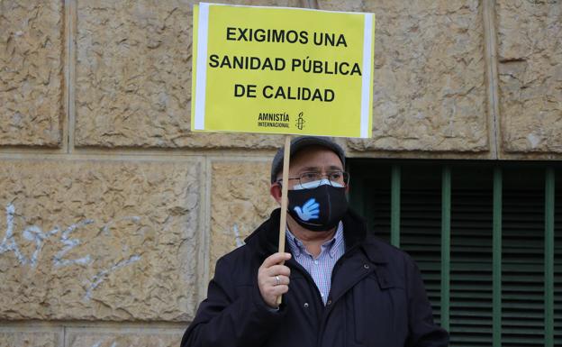 Un hombre sujeta un cartel por la sanidad pública en la concentración de Amnistía Internacional frente al centro de salud La Condesa.