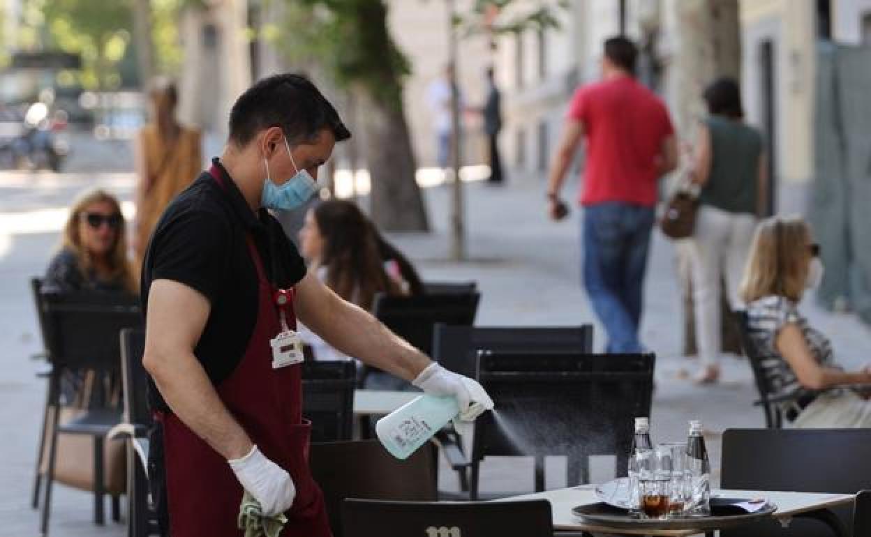 Un camarero desinfecta una mesa en la hostelería, uno de los sectores más afectados.