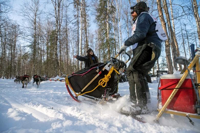 Dennis Kananowicz saluda a uno de los pocos espectadores a lo largo del sendero al comienzo de la Iditarod Trail Sled Dog Race, que se lleva a cabo en un circuito cerrado a través del desierto debido a la pandemia de coronavirus.