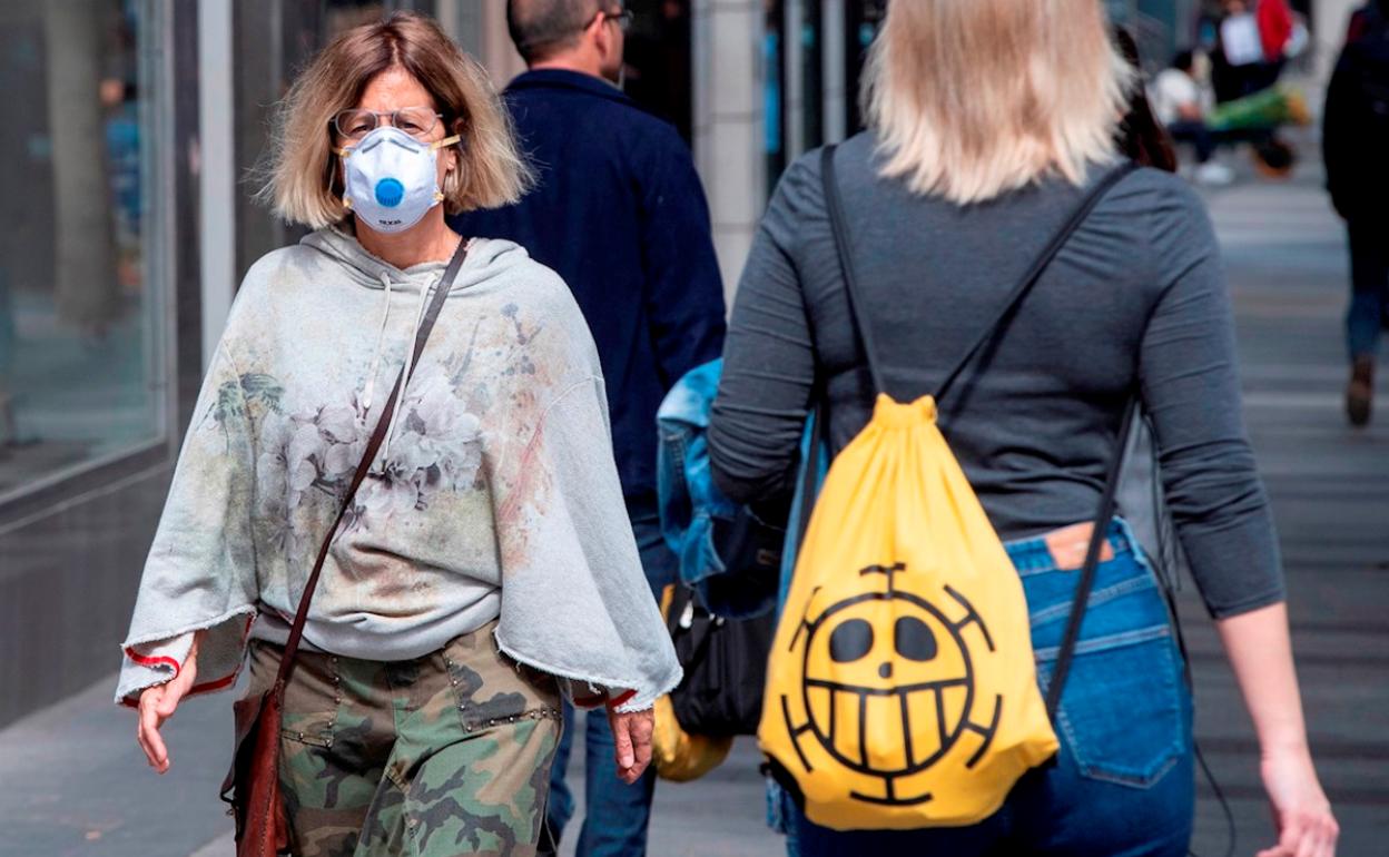 Una mujer pasea con una mascarilla. 