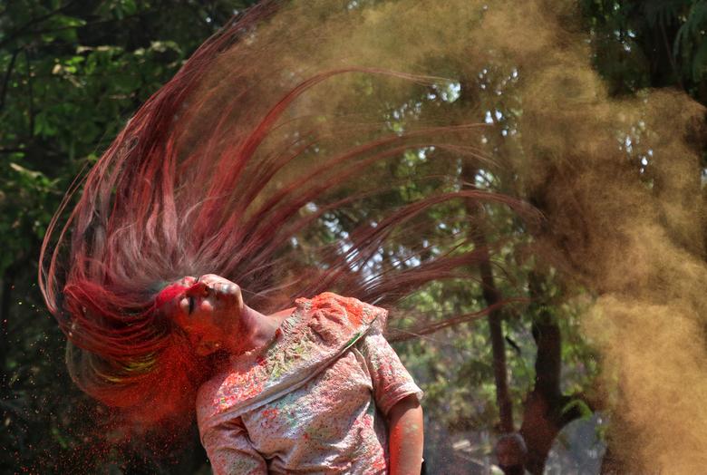 Una mujer untada con polvo de color sacude la cabeza para quitárselo durante las celebraciones de Holi en Mumbai, India.