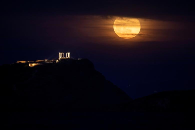 La luna llena, conocida como la "Super Luna Rosa", se eleva junto al Templo de Poseidón en Cabo Sunión, cerca de Atenas, Grecia.