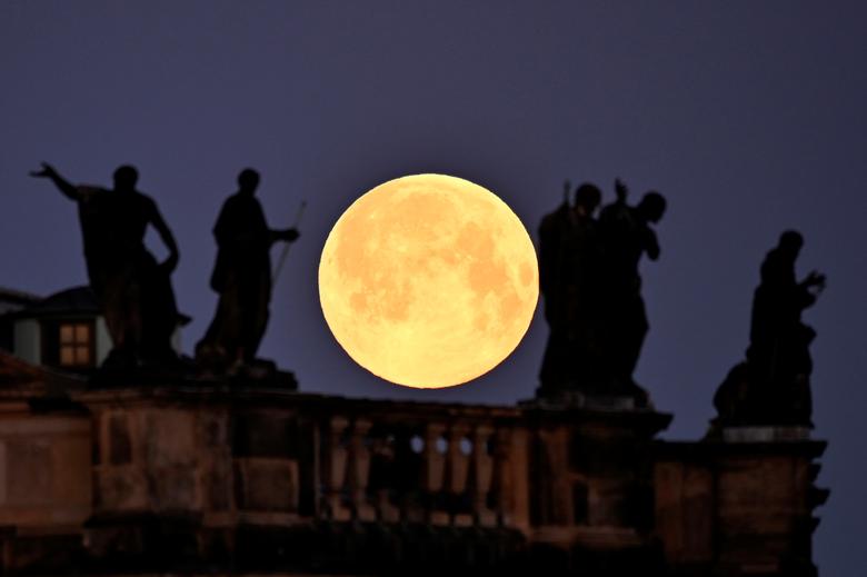 La superluna se ve detrás de las esculturas en el techo de la catedral de Dresde, Alemania. 