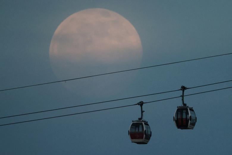 La luna llena, también conocida como Supermoon, se eleva sobre el teleférico de Emirates Air Line en Londres.