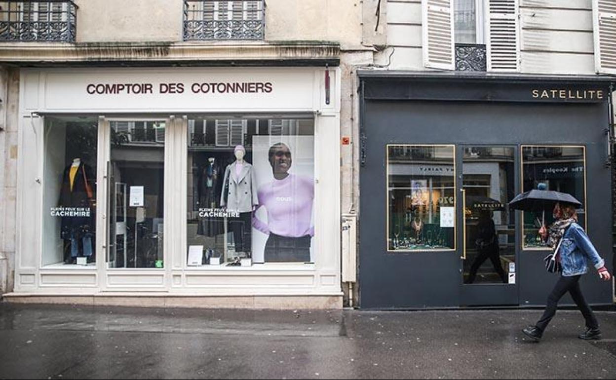 Una mujer frente a varias tiendas cerradas en París.