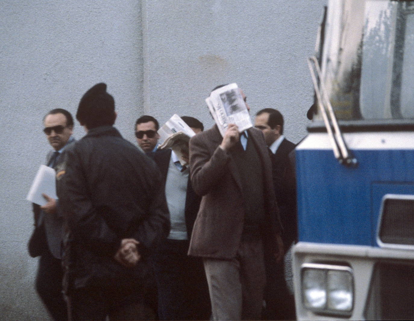 30-3-1987.Los 38 acusados en el ´juicio de la colza´ se tapan la cara con periódicos a su llegada a sala habilitada, en el auditorium de la Casa del Campo, donde se inició esta mañana la lectura de un resumen de la causa, por el secretario judicial.