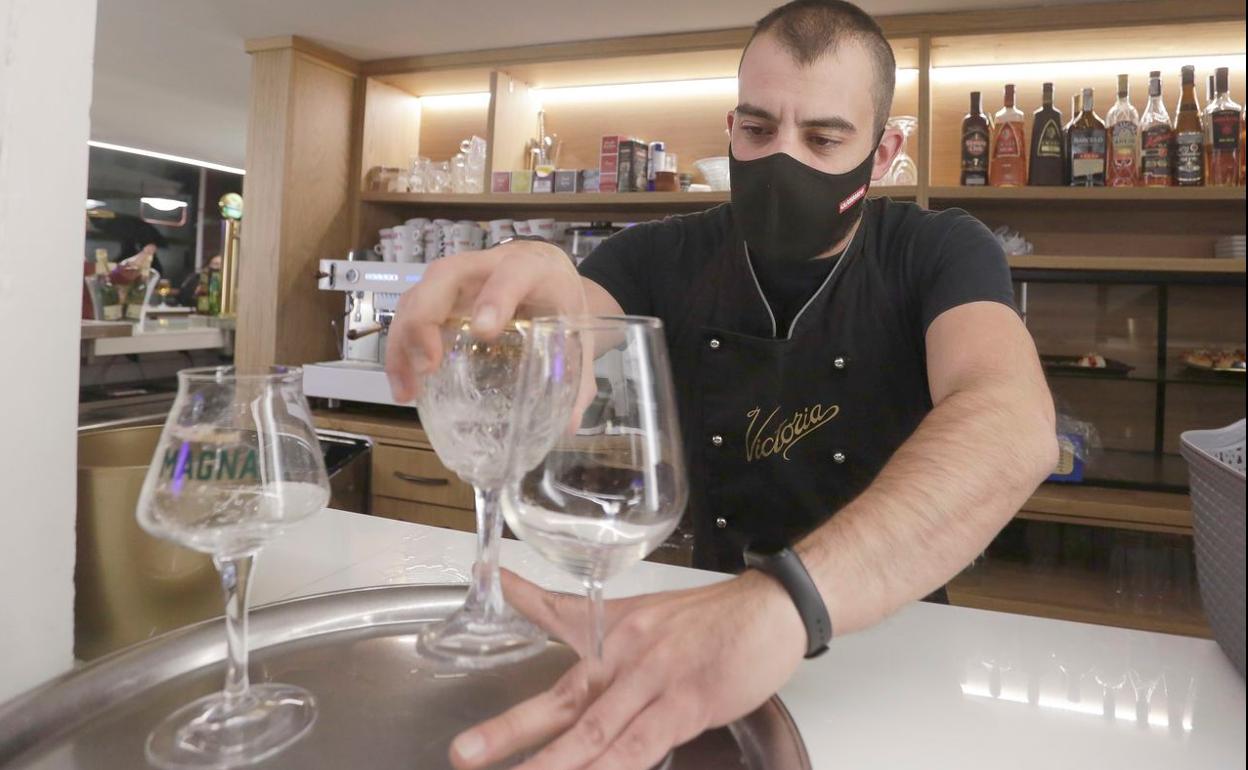 Un hostelero recoge varias consumiciones en León capital. Desde este martes se recupera el cierre de interiores. 