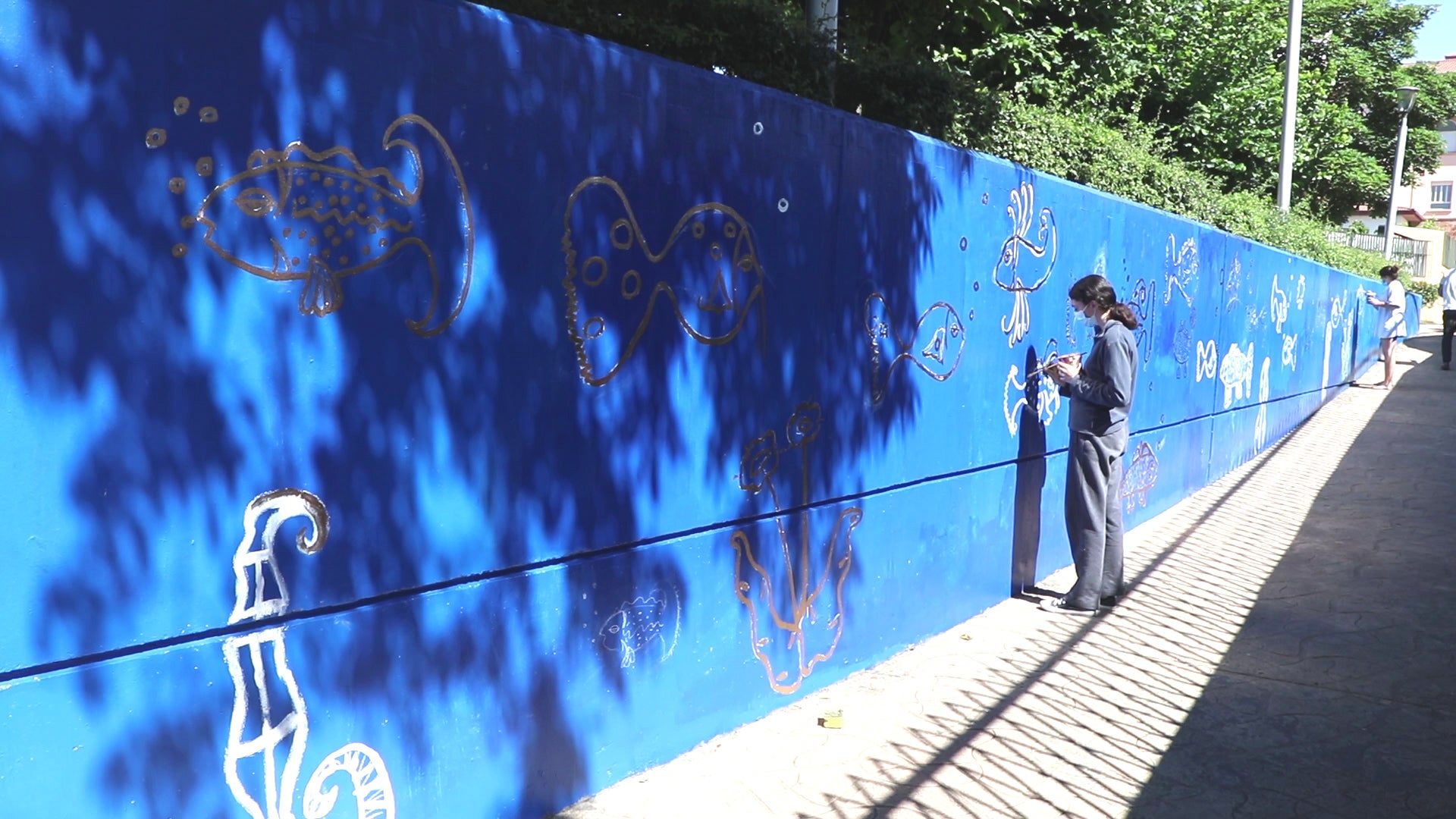 Las reconocibles figuras del fallecido artista leonés Miguel Escanciano plasman una nueva imagen en oscurecida travesía de esta calle de la ciudad, donde la colaboración entre El Corte Inglés, el artista Carlos Cuenllas y unas alumnas del Colegio Leonés y Maristas ha hecho posible dar nueva vida a un muro sin estética.