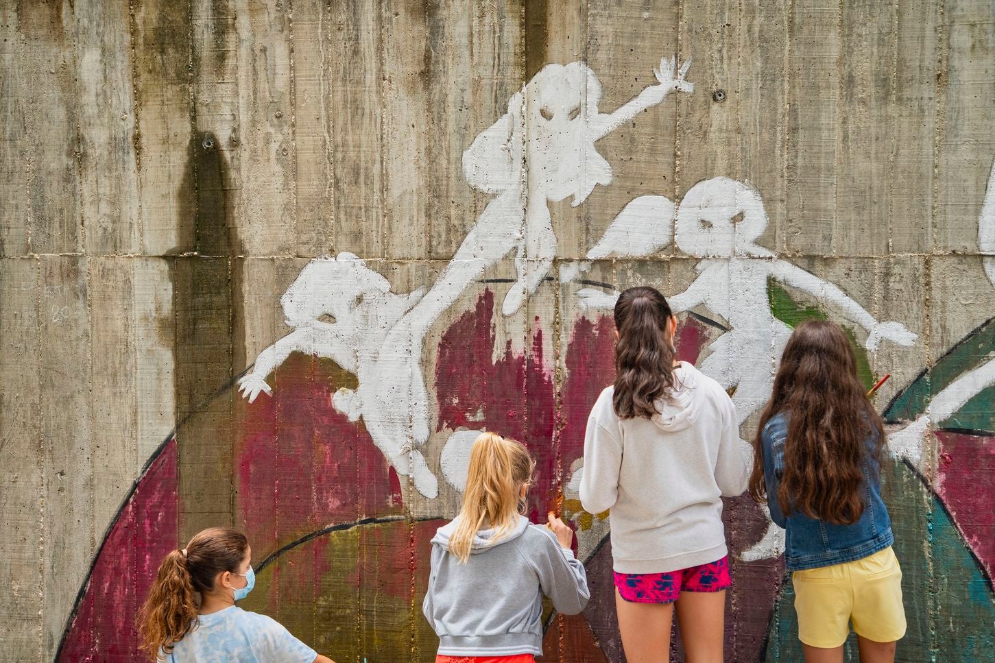 Un mural de superheroínas visibilizará el deporte femenino en el CEIP Margarita Salas de Arroyo (Valladolid), centro vencedor del reto de Afedecyl, impulsado por Iberdrola. En la imagen las niñas que están pintando el mural, junto a los responsables de la iniciativa y profesoras del centro; entre ellos, el dibujante leonés 'lolo'. 