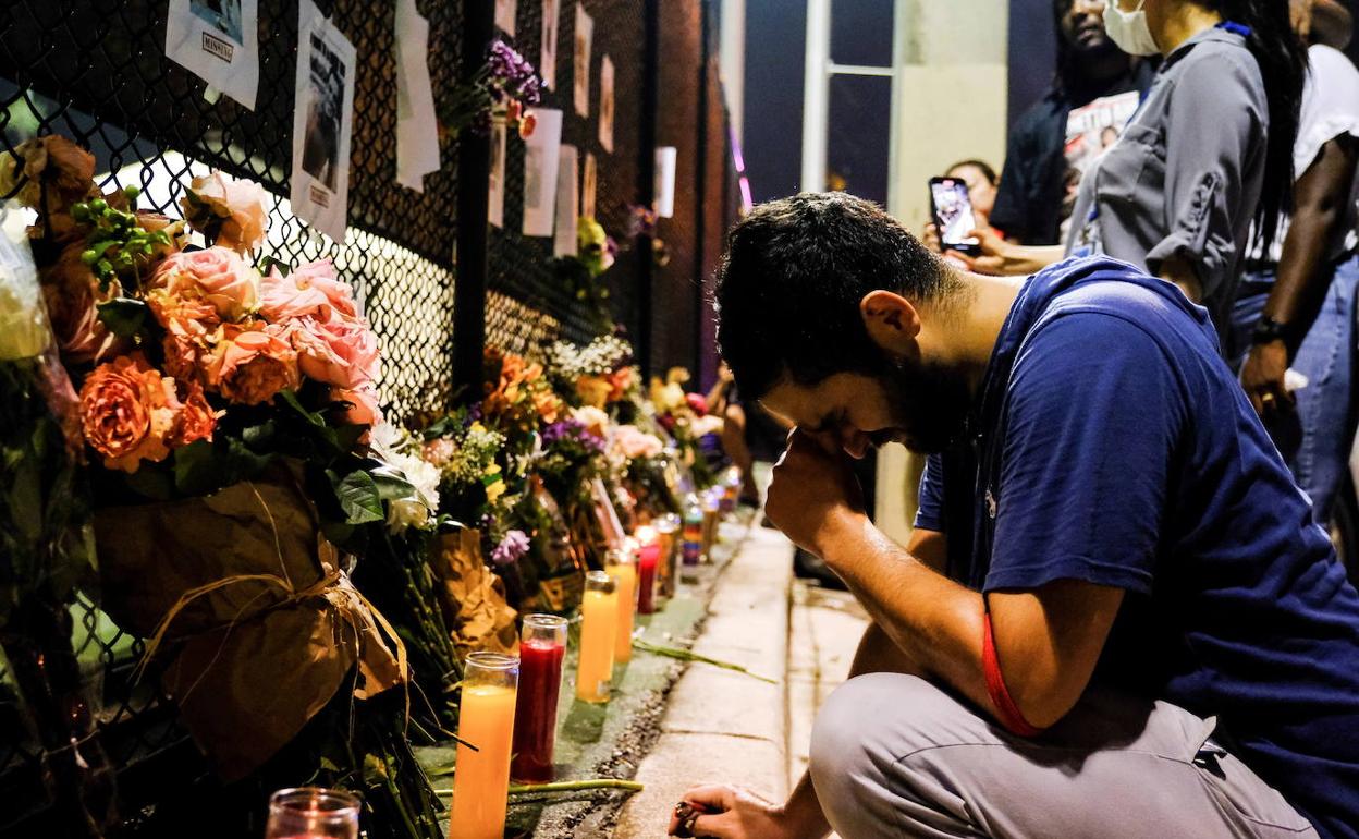 Un joven se postra ante el memorial por las víctimas del derrumbe del eficio en Miami.