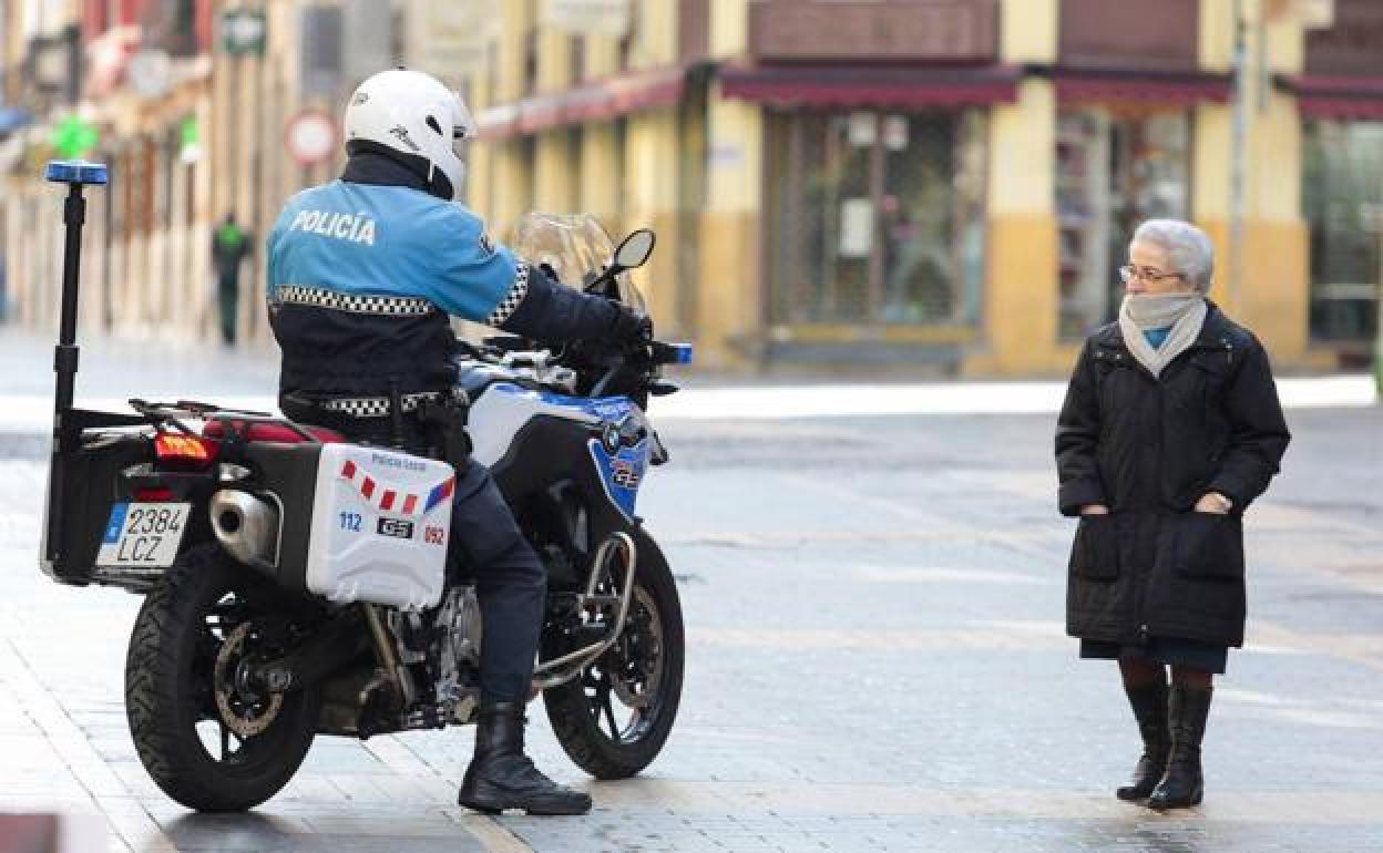 Un policía se dirige a una mujer que camina por la calle durante el confinamiento domiciliario.