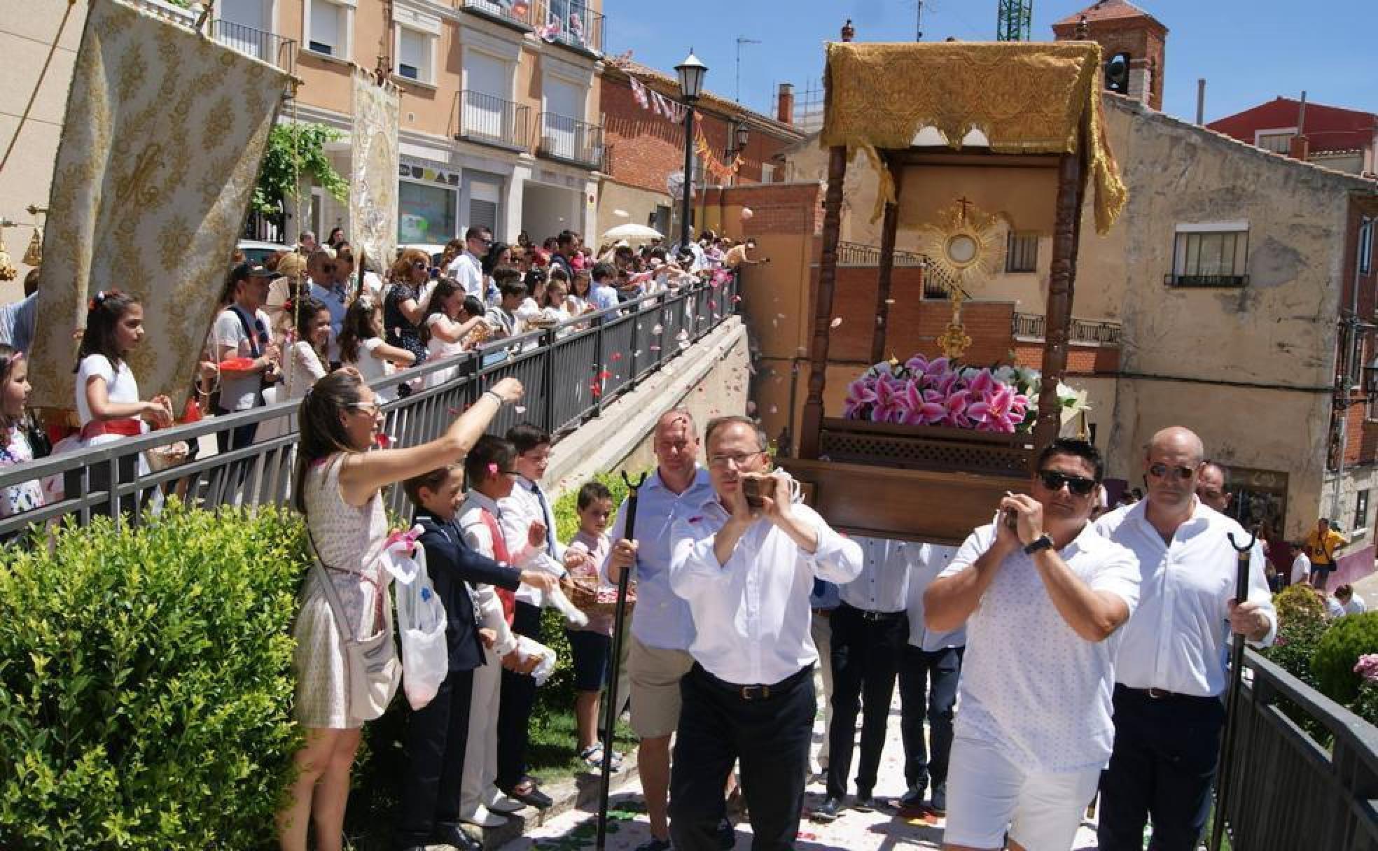 Vecinos de todas las edades y niños de Primera Comunión tiran pétalos de rosa al paso de la custodia el día del Corpus en Zaratán.