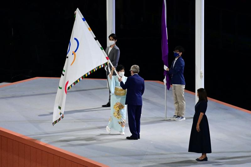El presidente del COI, Thomas Bach, recibe la bandera olímpica.