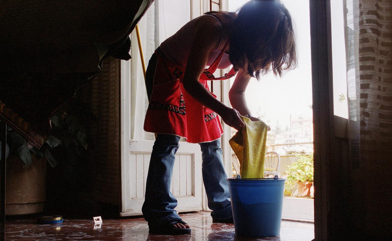 Empleada de hogar friega el suelo de una casa.