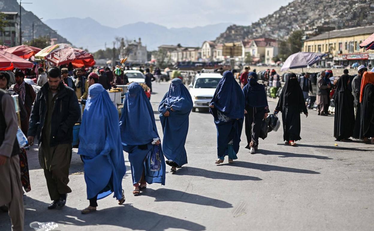 Un grupo de mujeres camina por un mercadillo en una calle de Kabul.