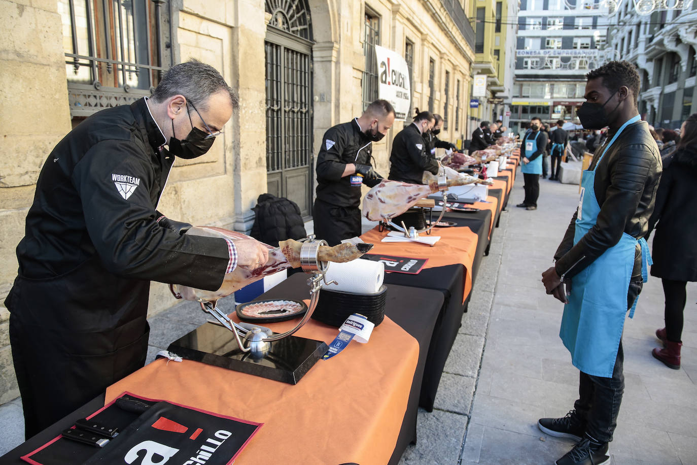 Centenares de personas participan en el corte de platos de jamón por una acción benéfica.