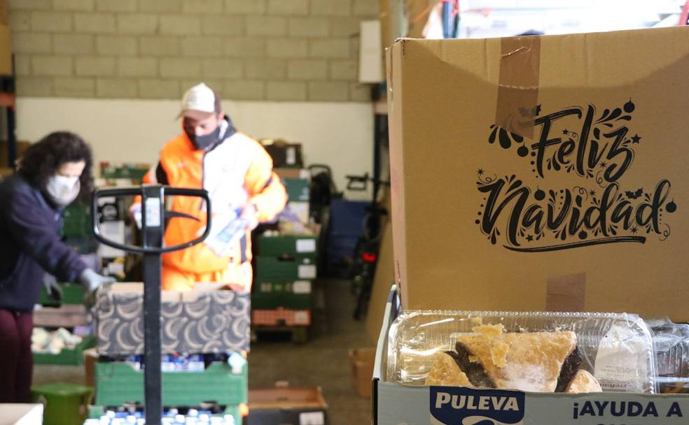Dos voluntarios del Banco de Alimentos de León colocan las cajas con las donaciones tras la Gran Recogida 2021 para preparar los carros que ayuden a más de un millar de familias.