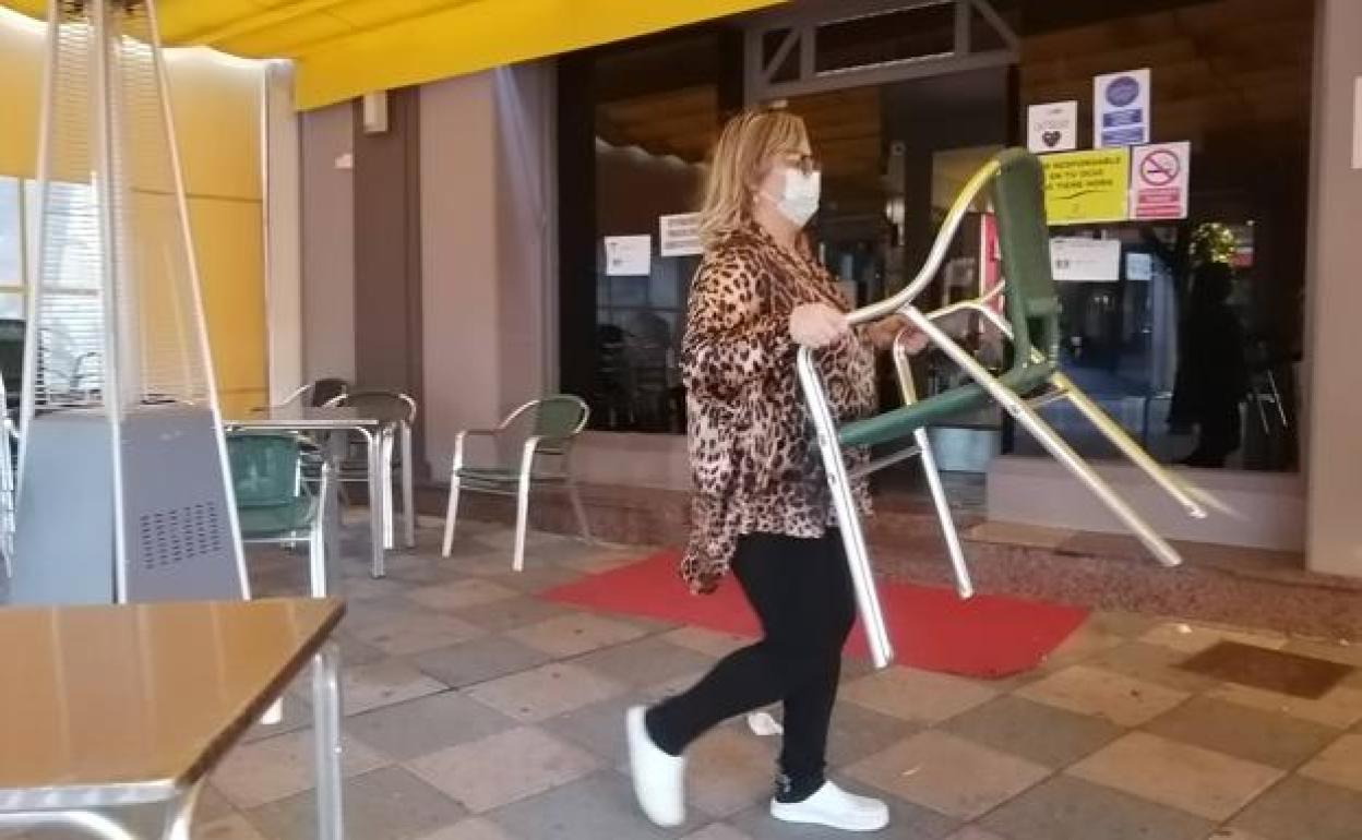 Una mujer coloca la terraza de un establecimiento de hostelería. 