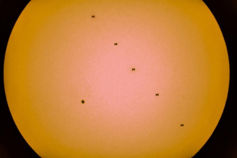 Una imagen compuesta de cinco fotografías separadas tomadas con una sola cámara fija muestra una mancha solar y la Estación Espacial Internacional en silueta mientras pasa a través del Sol, vista desde cerca de Tbilisi, Georgia, el 19 de junio de 2021.