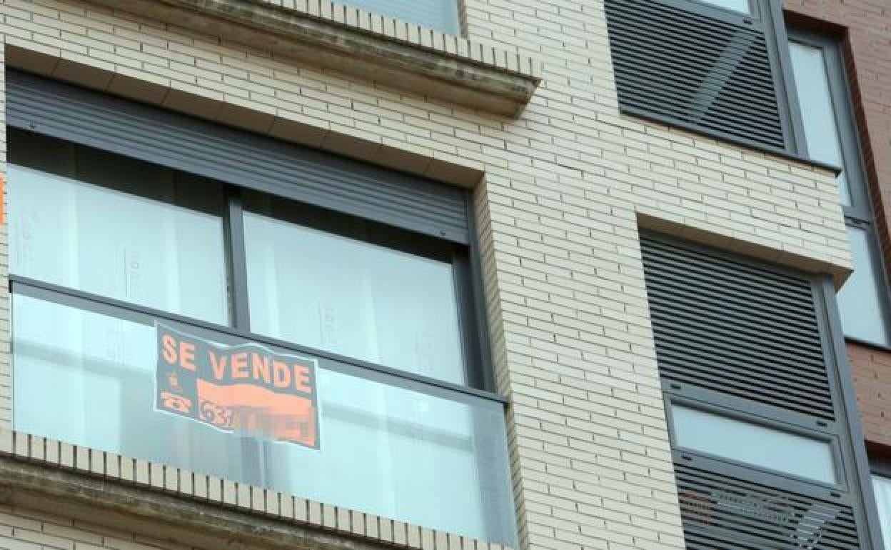 Imagen de un piso en venta con un cartel informativo en una de sus ventanas. 