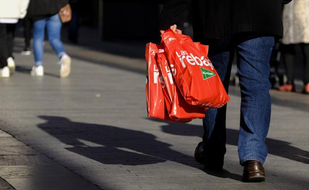 Un hombre camina con bolsas de las rebajas en una calle de Madrid. 