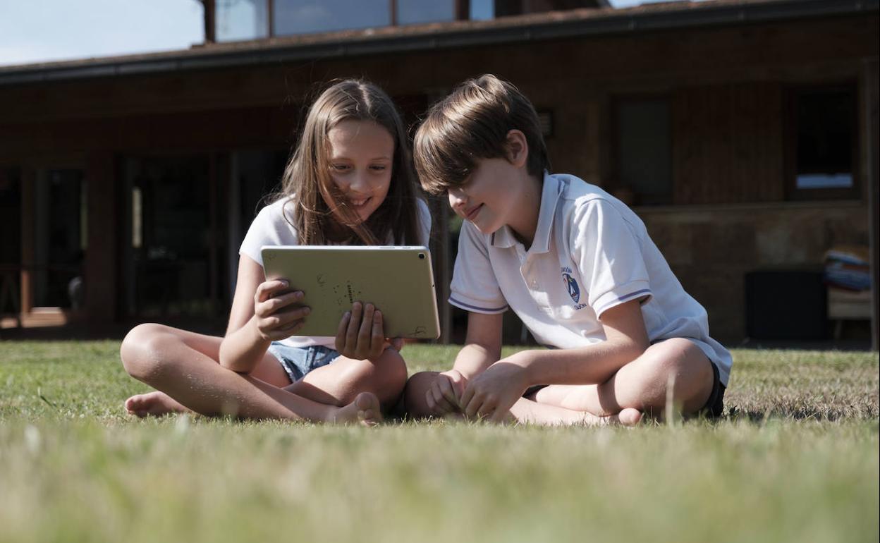 Dos niños, conectados a internet con una tablet.