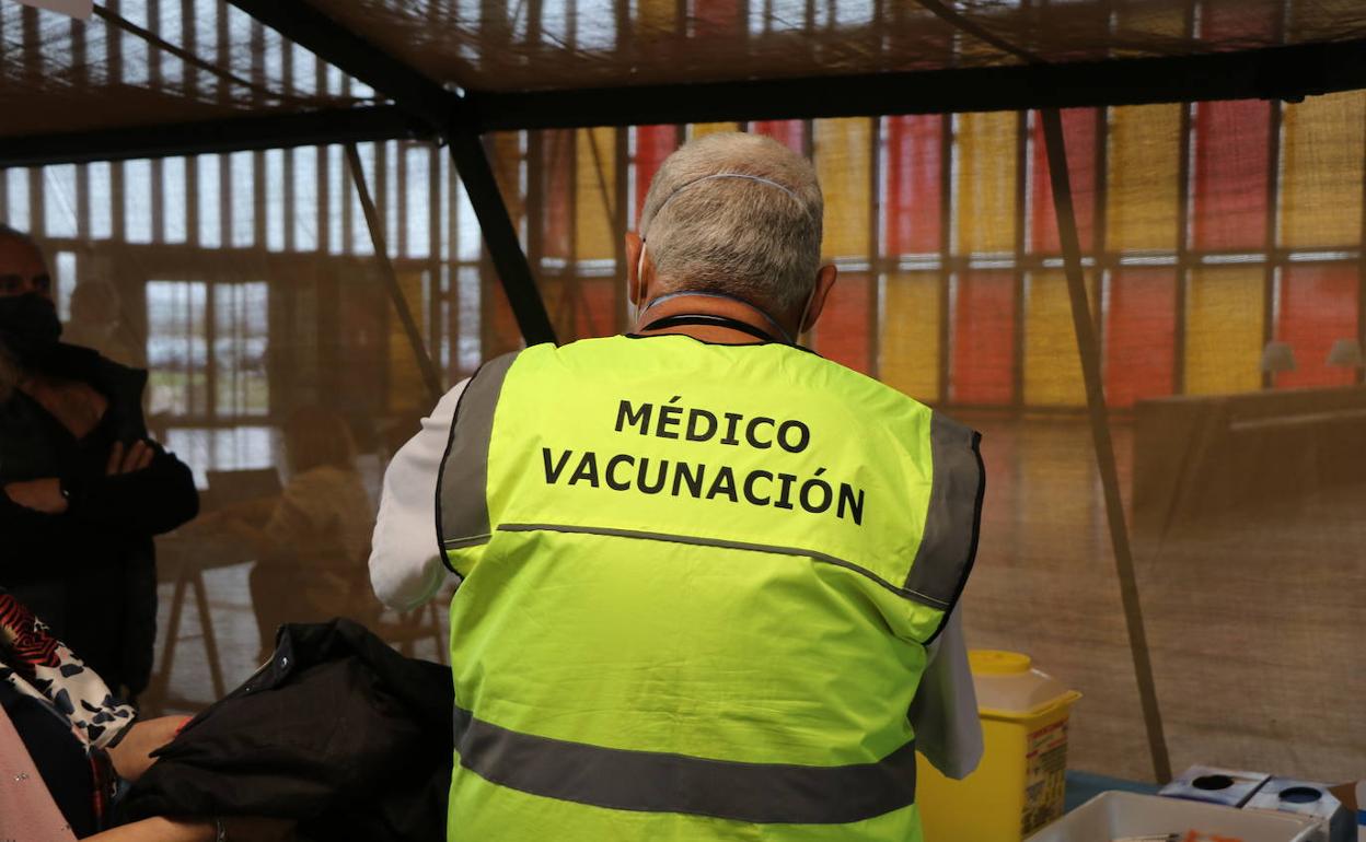 Un médico vacuna con la tercera dosis contra la covid en el Palacio de Exposicioens de León.