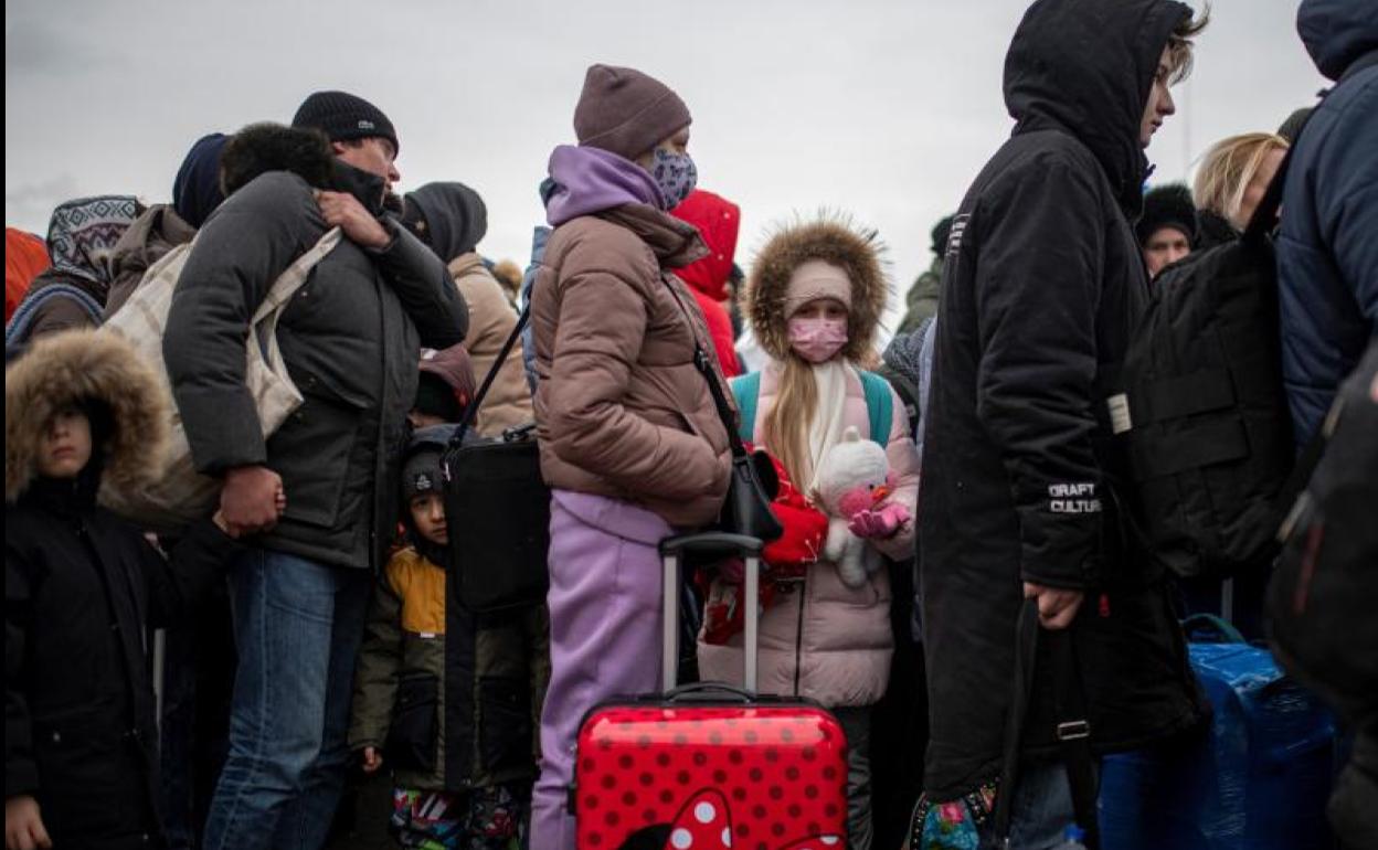 Varias personas y niños esperan para cruzar a Rumanía, en el paso fronterizo de Porubne.