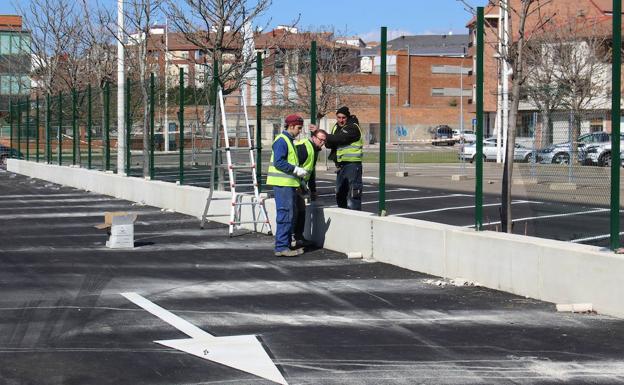 Algunos operarios trabajan en los remates del aparcamiento de caravanas de La Granja. 