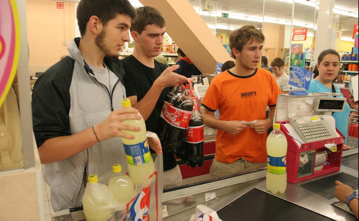Jovenes compran bebida en un supermercado de Vitoria.