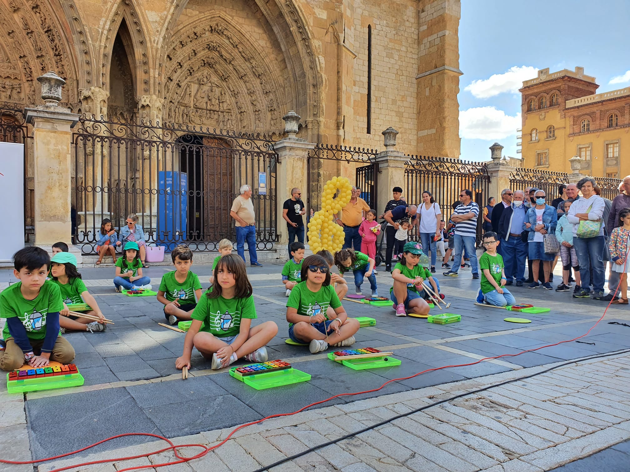 Música solidaria a los pies de la Catedral. Los pequeños alumnos de '+QMÚSICA' han sacado sus instrumentos en la plza de la Regla para mostrar las acciones sociales que realiza la Sociedad de San Vicente de Paúl.