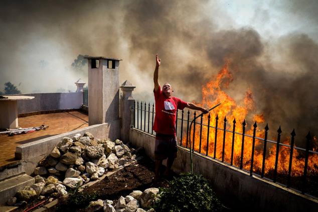 Un hombre echa agua sobre las llamas en Canecas, a las afueras de Lisboa.
