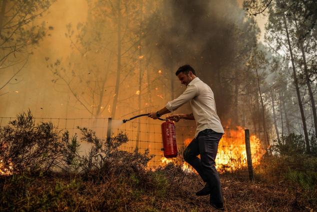Un hombre combate las llamas con un extintor en Boa Vista, Leiria. Cuatro focos activos en los distritos de Santarem y Leiria han obligado a movilizar más de 1.100 trabajadores, 320 vehículos y 13 aviones para las labores de extinción, según datos de Protección Civil.