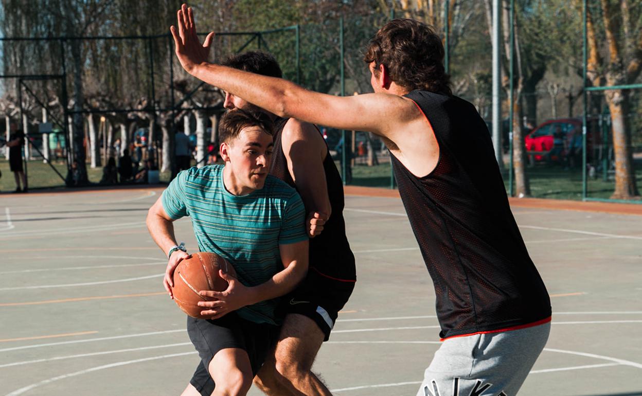 Imagen de tres jugadores disputanto un partido de baloncesto. 