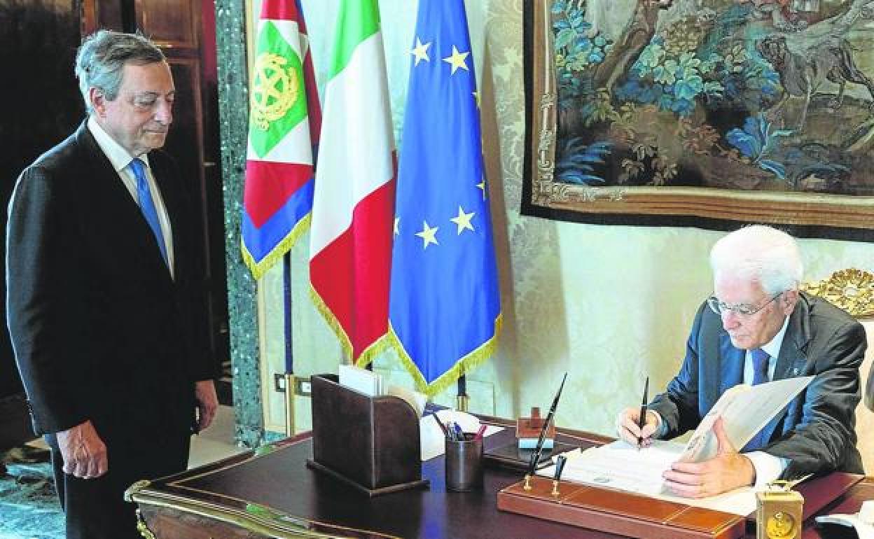 Draghi observa cómo el presidente italiano, Sergio Mattarella, firma el decreto de disolución del Parlamento. 