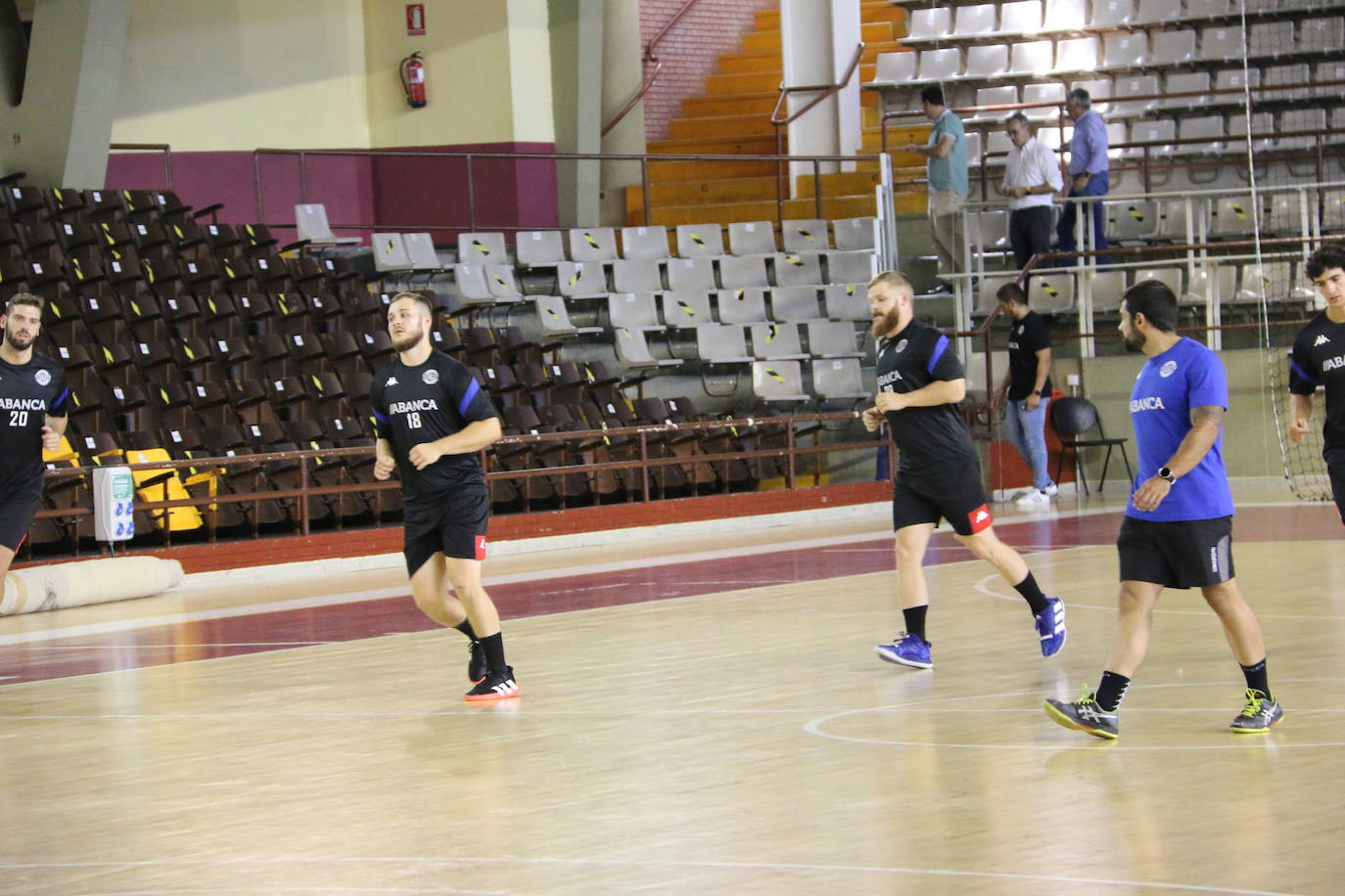 La plantilla del Ademar realiza flexiones en medio de la cancha del Palacio de los Deportes. 